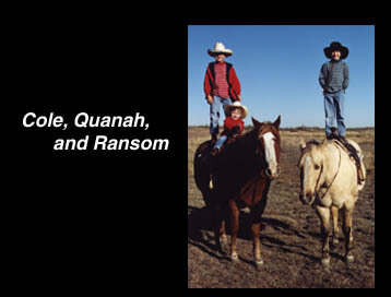 Cole and Ransom standing on the backs of their horses; Quanah sits in front of Cole. 